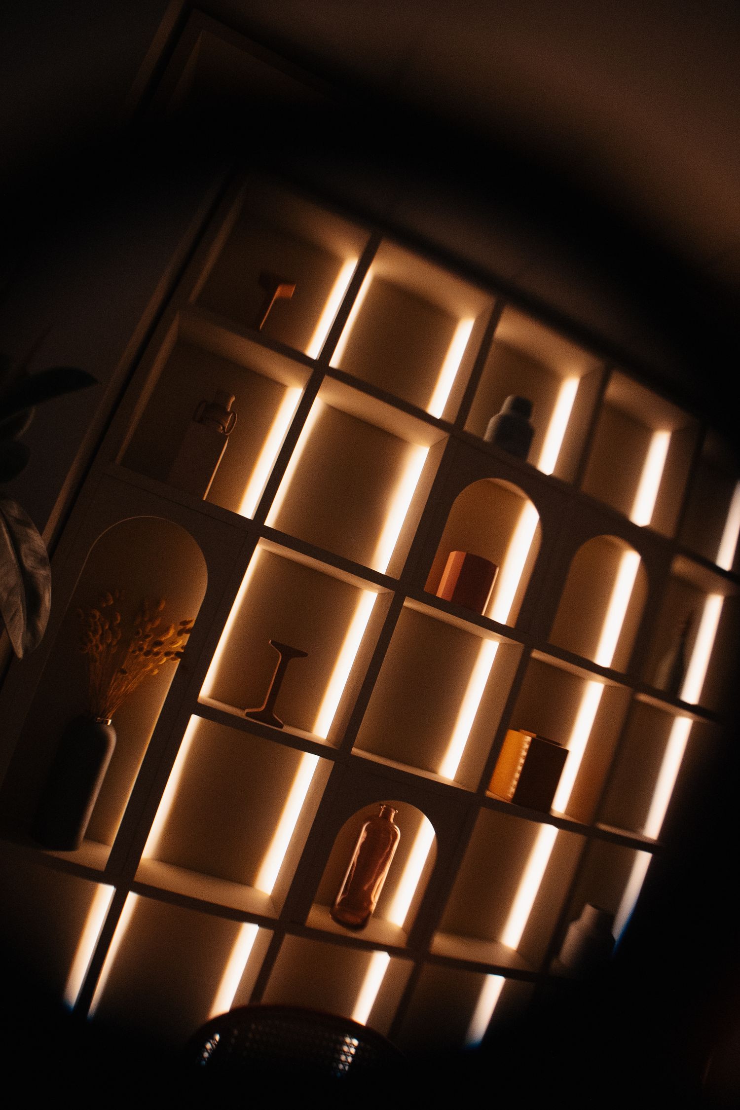 Backlit wooden wall display with vertical lighting creating dramatic shadows.