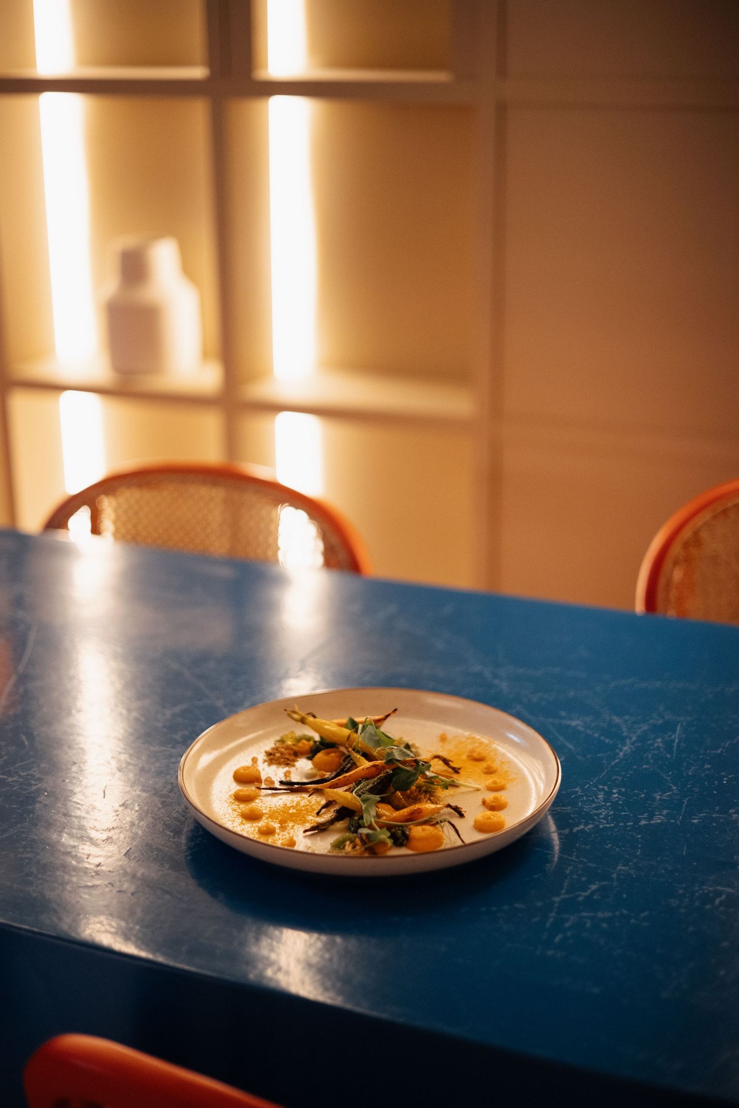 Elegantly plated dishes on a blue table with warm lighting create an upscale dining atmosphere.