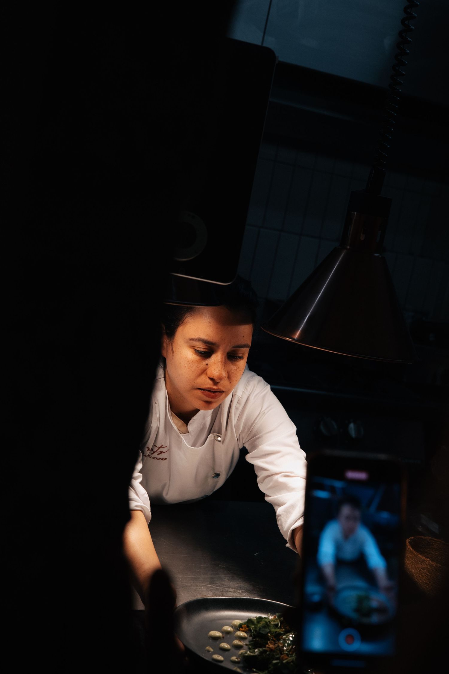 Chef working in dark kitchen environment with focused lighting on prep area.