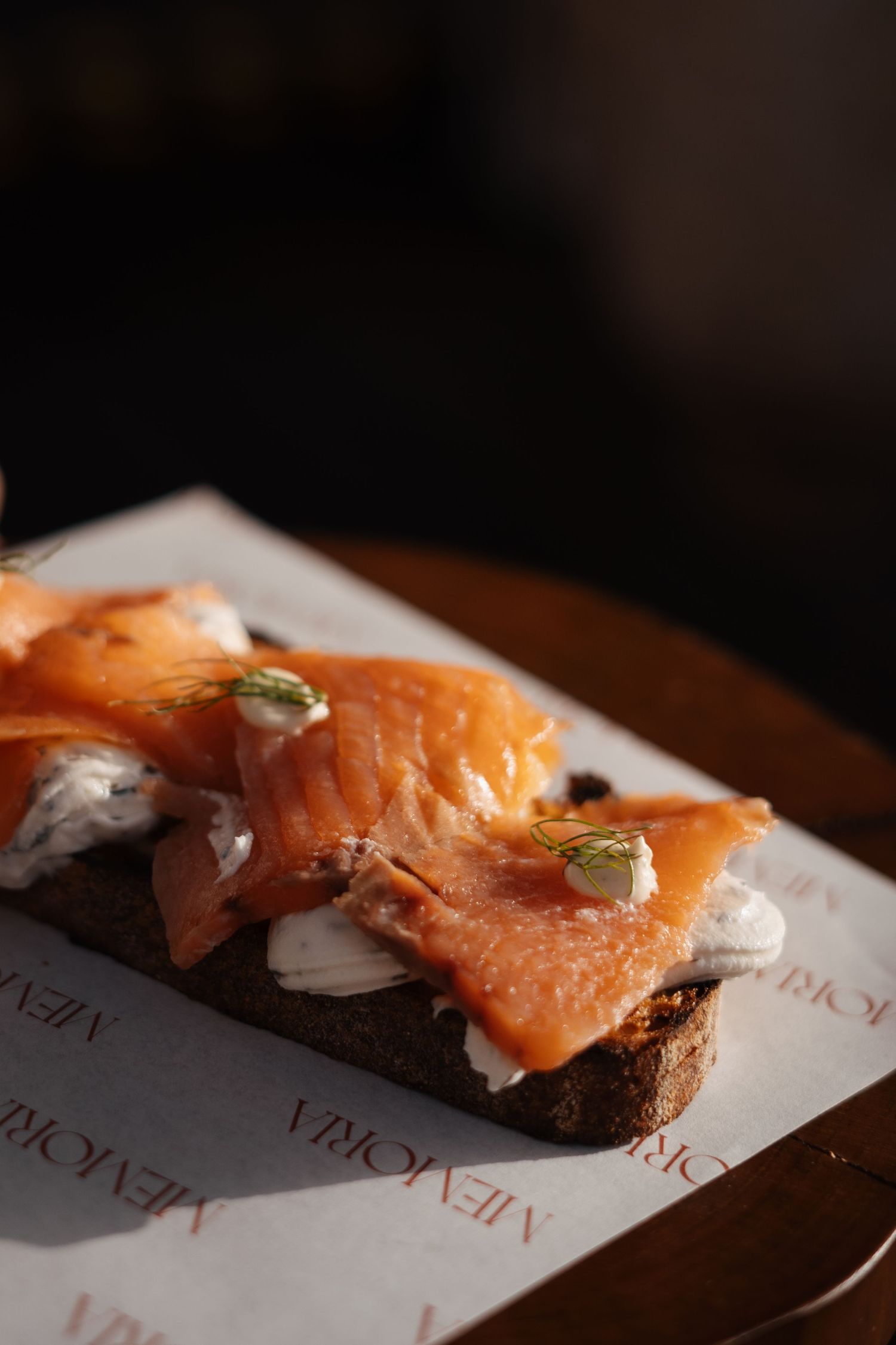Fresh salmon appetizer served on dark bread with garnish.