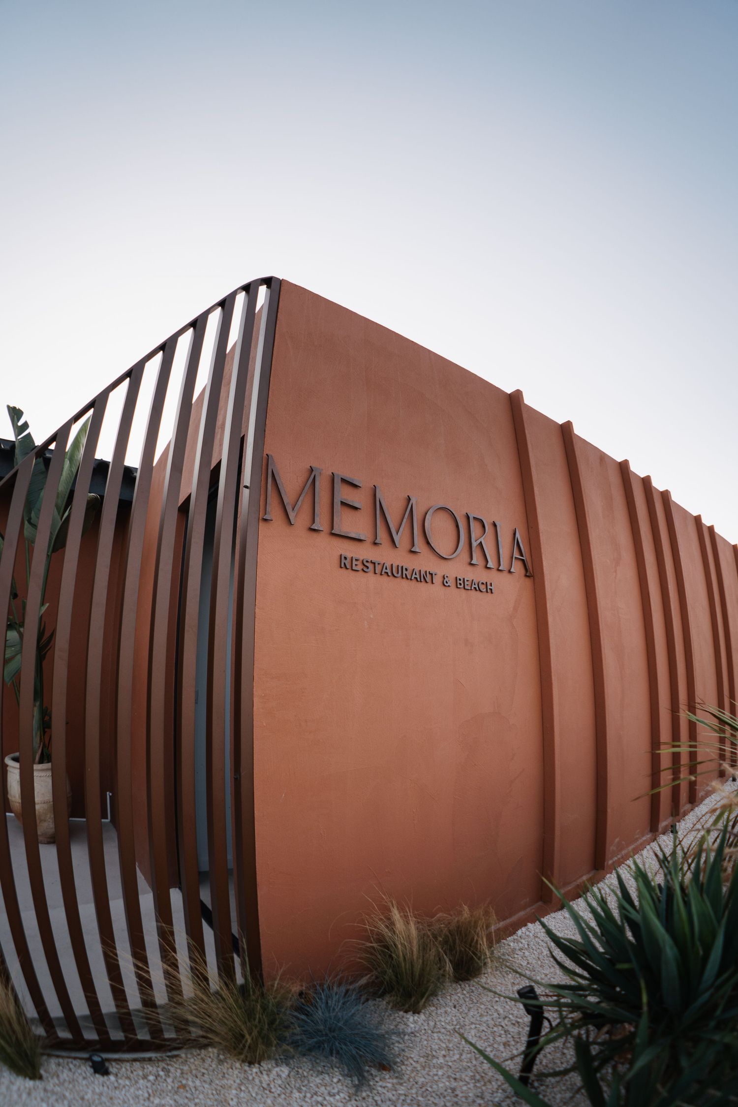 Modern terracotta colored restaurant exterior with geometric metal fence design.