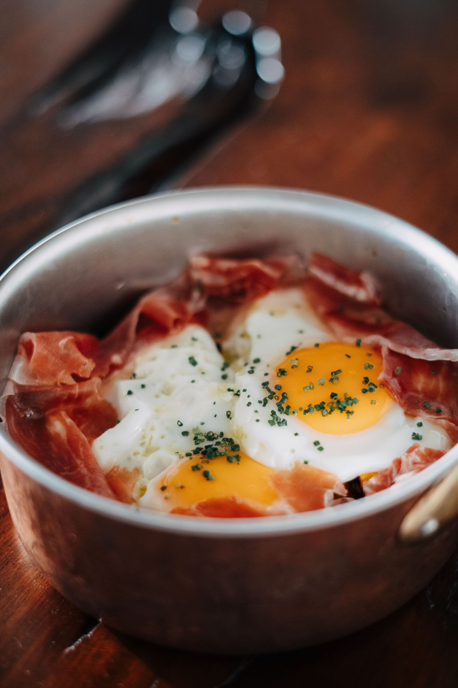 Baked eggs with prosciutto in a white ceramic dish.