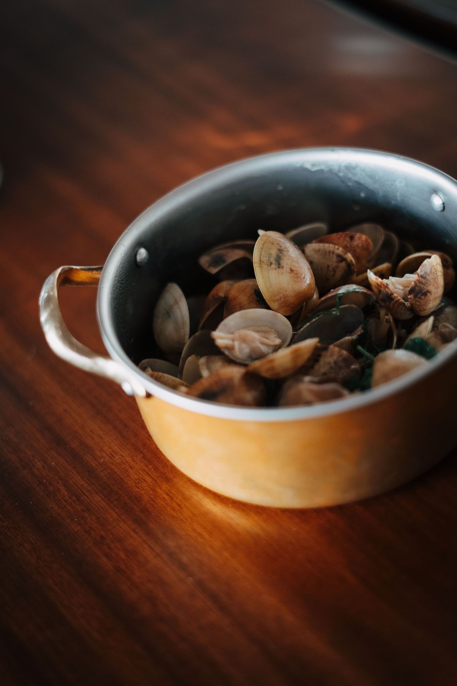 Bowl of steamed clams and mussels on wooden table.