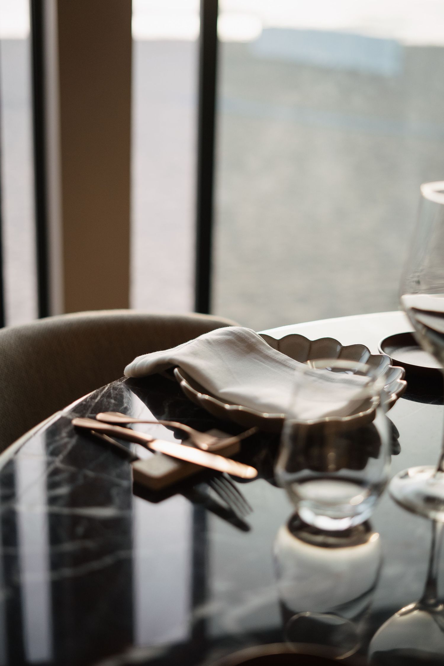 Artistic close-up of gloved hands and dining utensils on a dark reflective surface.