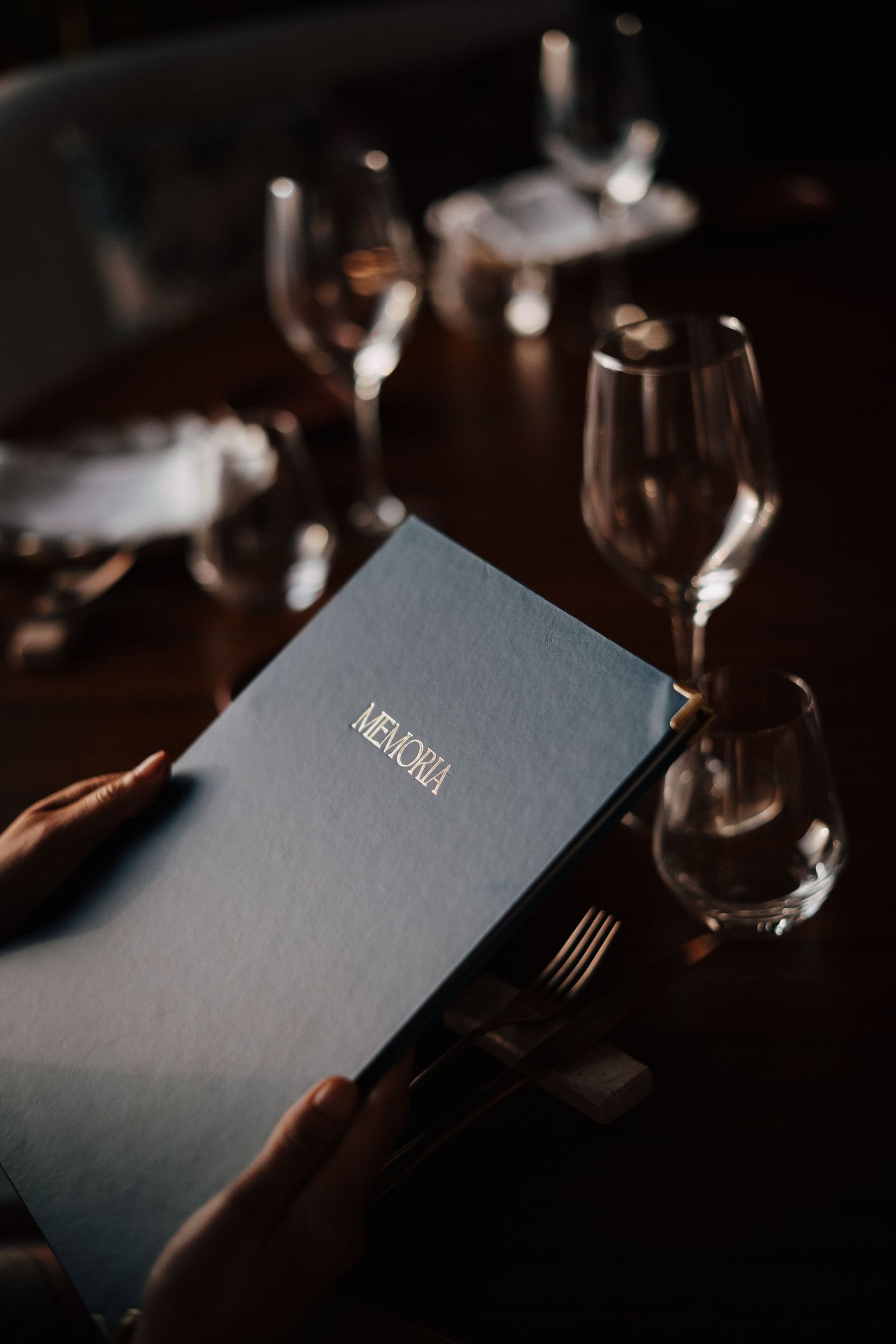 Dark blue menu or wine list on an elegant dining table with wine glasses.