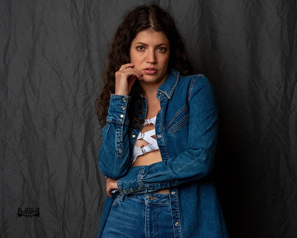 Four fashion portraits showing a person wearing a denim jacket and cropped top against a dark textured background.