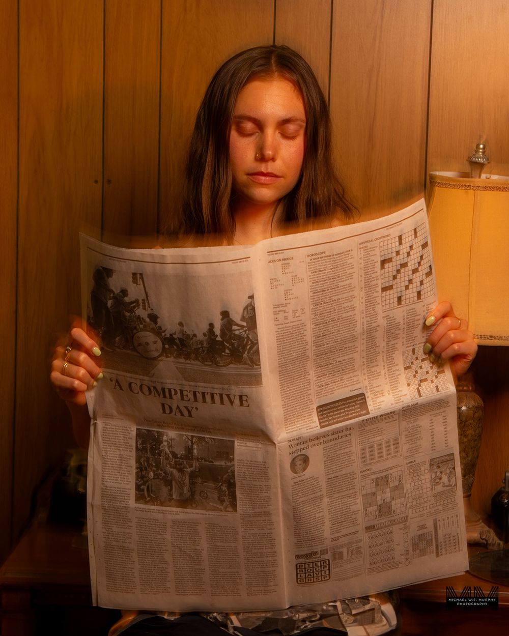 Someone reading a newspaper in warm lighting against wooden paneled walls in a contemplative scene.
