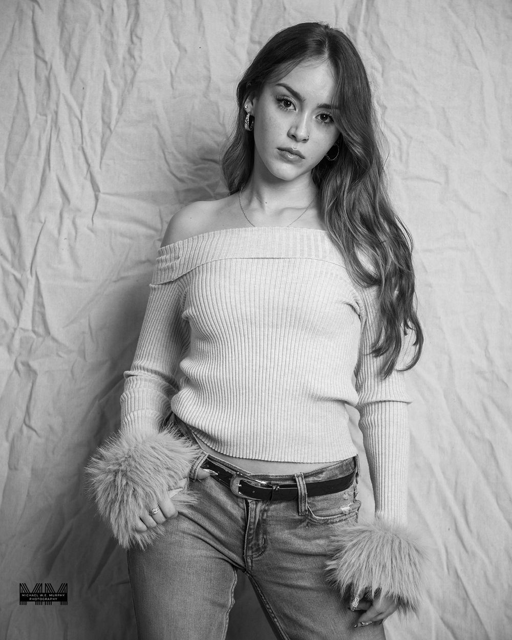 Black and white fashion portraits of a woman in a ribbed top and jeans posing against a textured backdrop.