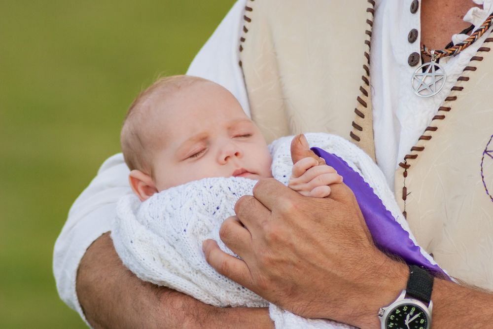 A baby being held by it's father after it's baby naming ceremony.