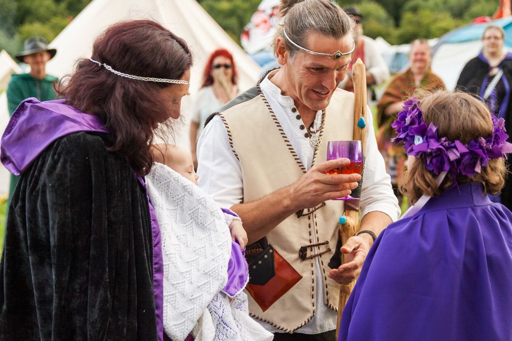 A father taking a libation during an outdoor pagan baby naming ceremony.