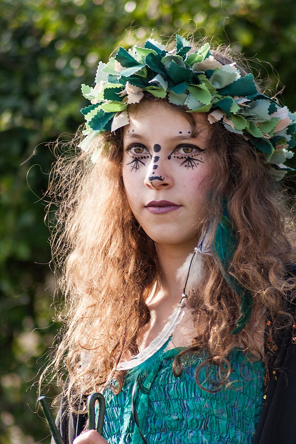 Candid portrait of a young lady in green with a flower crown at an outdoor pagan baby naming ceremony.
