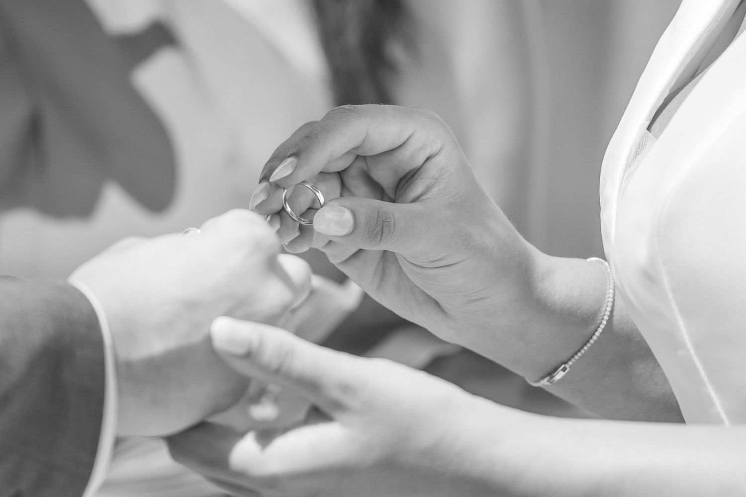 Close-up shot of hands exchanging rings during wedding ceremony.