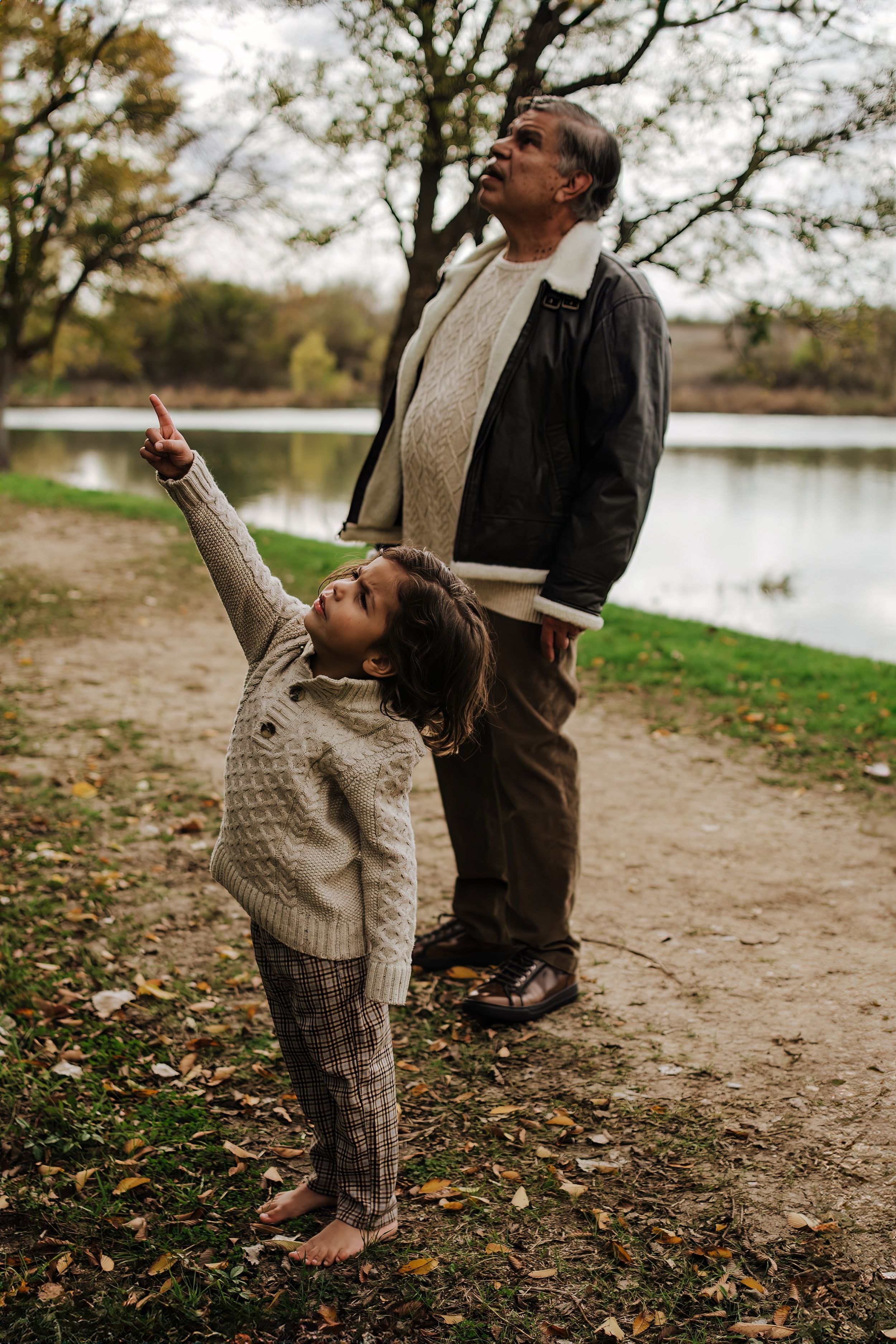 A heartwarming moment shared between family members on a path by a lake during fall.