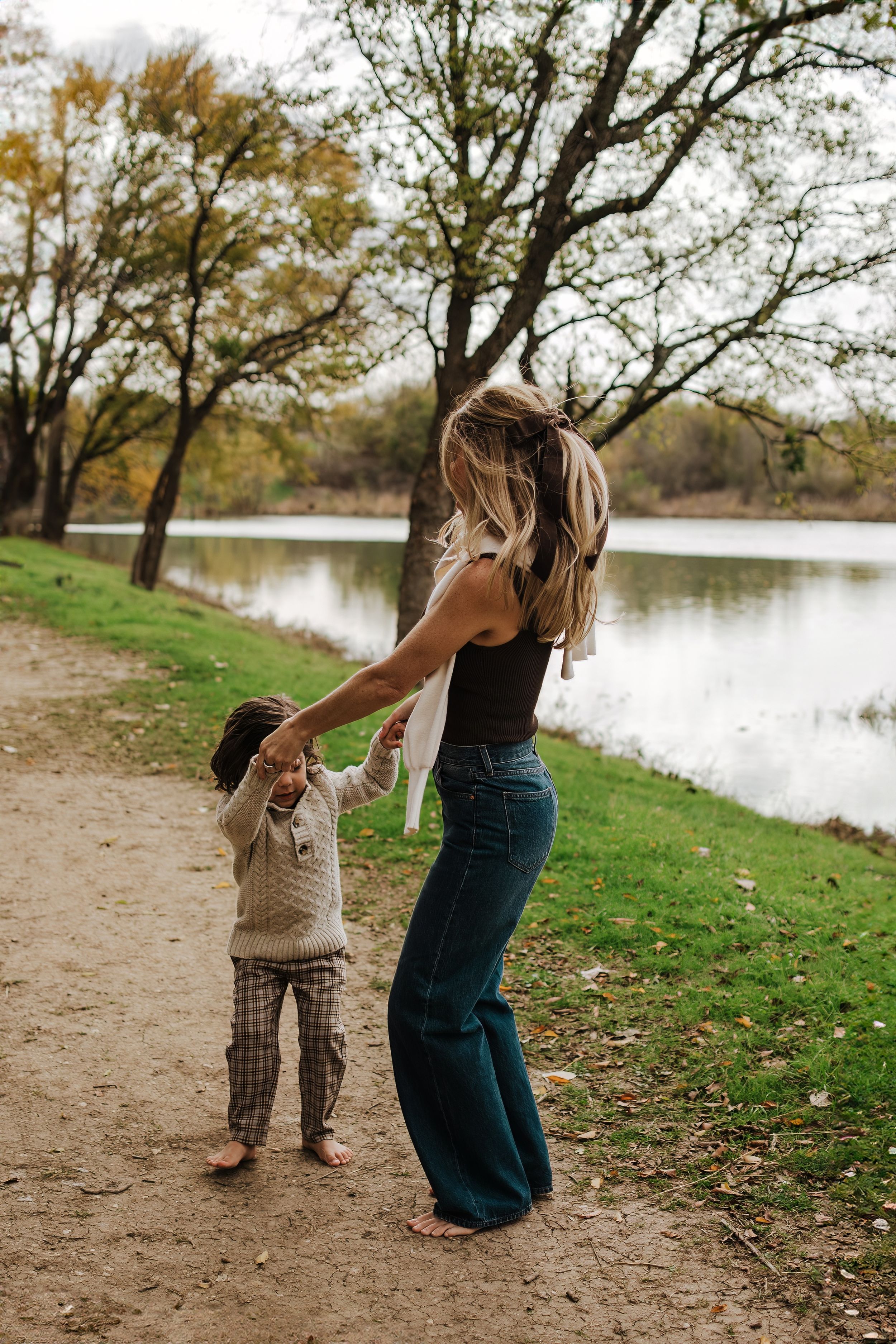 Joyful playtime between family members on a dirt path surrounded by autumn foliage.