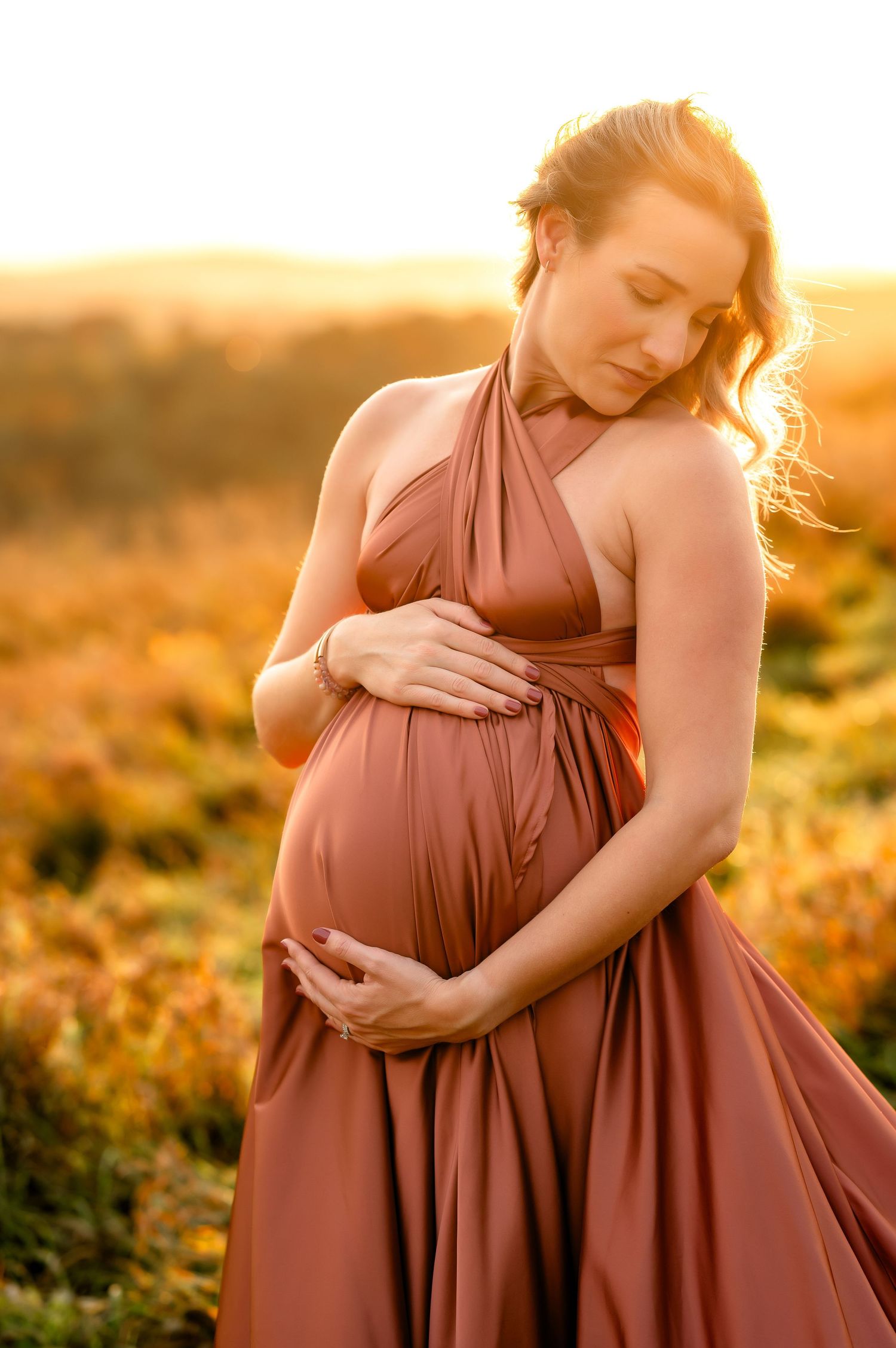 Maternity photo of woman in flowing dress during golden hour in field created by Storms Photography in Pennsylvania.