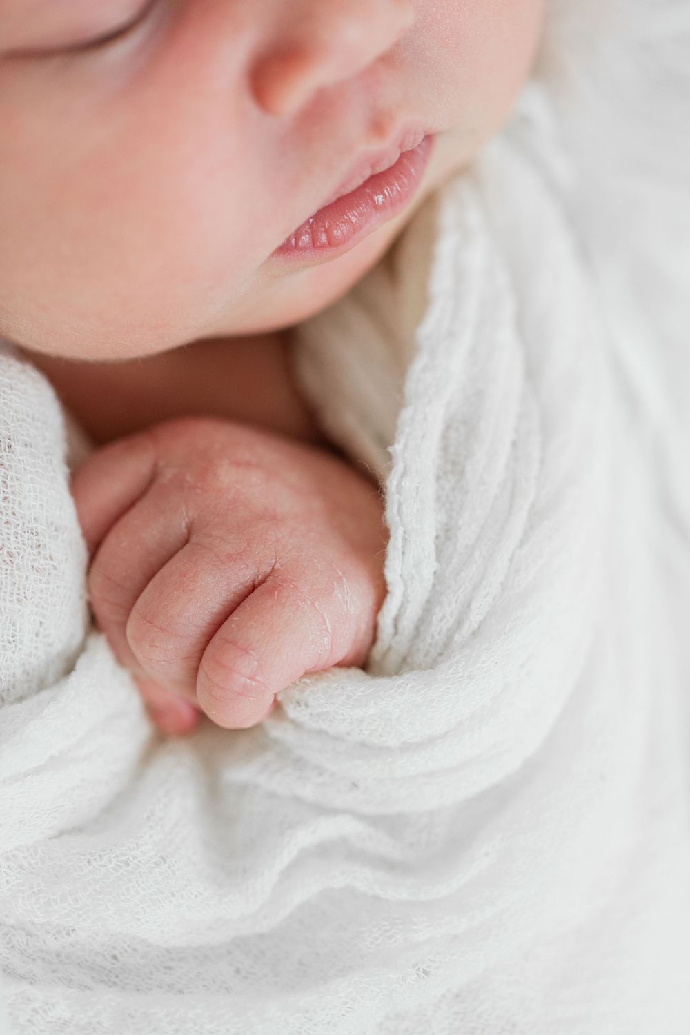 Close-up view of a newborn baby's tiny features and delicate white blanket wrapping showing four tender details.