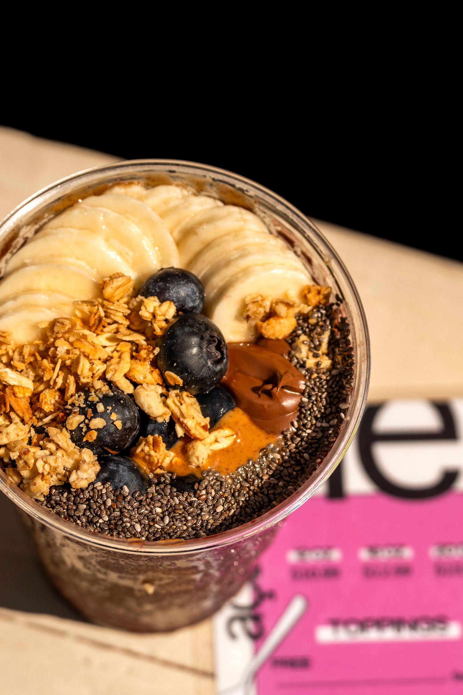 Smoothie bowl topped with banana slices, blueberries, granola and chia seeds.