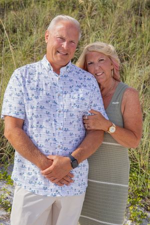 Couple in summer attire sharing affectionate moments against tall grass background.
