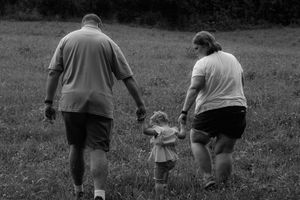 A black and white candid photo of people walking together in a grassy field.