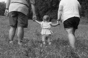 A black and white image of people walking through tall grass.
