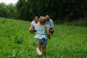 A candid family moment captured in a vibrant green summer meadow.