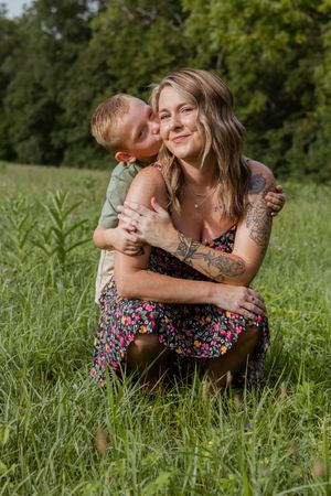 Tender moments shared between two people lying in tall grass on a sunny day.