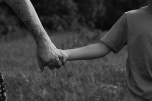 Black and white close-up shots of hands holding and connecting in an emotional sequence.