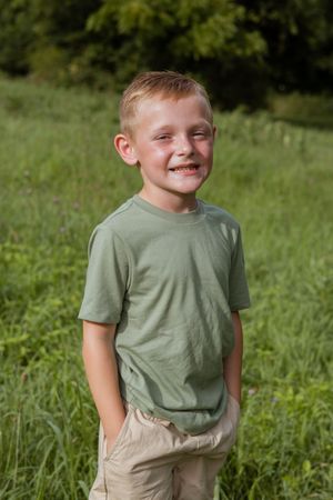 A child in a green t-shirt shows different playful expressions while posing outdoors.