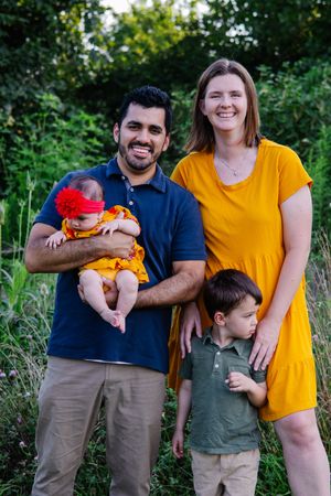 Family wearing coordinated yellow and navy outfits poses together in a natural outdoor setting.