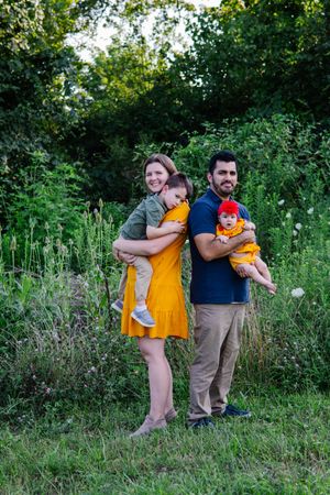 Family members share candid moments together in a lush green outdoor setting.