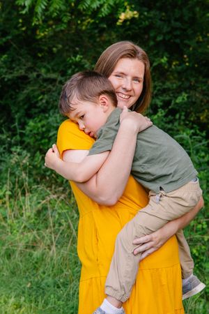 A tender family embrace captured outdoors with yellow and olive green clothing.