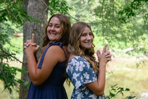 Friends sharing laughter and embracing during an outdoor summer photoshoot by a pond.