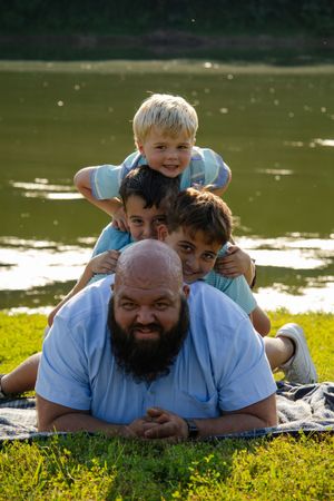 Playful moments captured on grass by a lake during summer photoshoot.