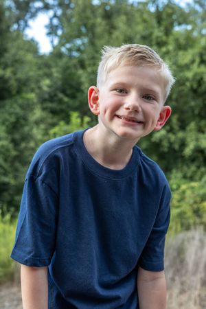 Close up portrait of young child in navy blue t-shirt outdoors.