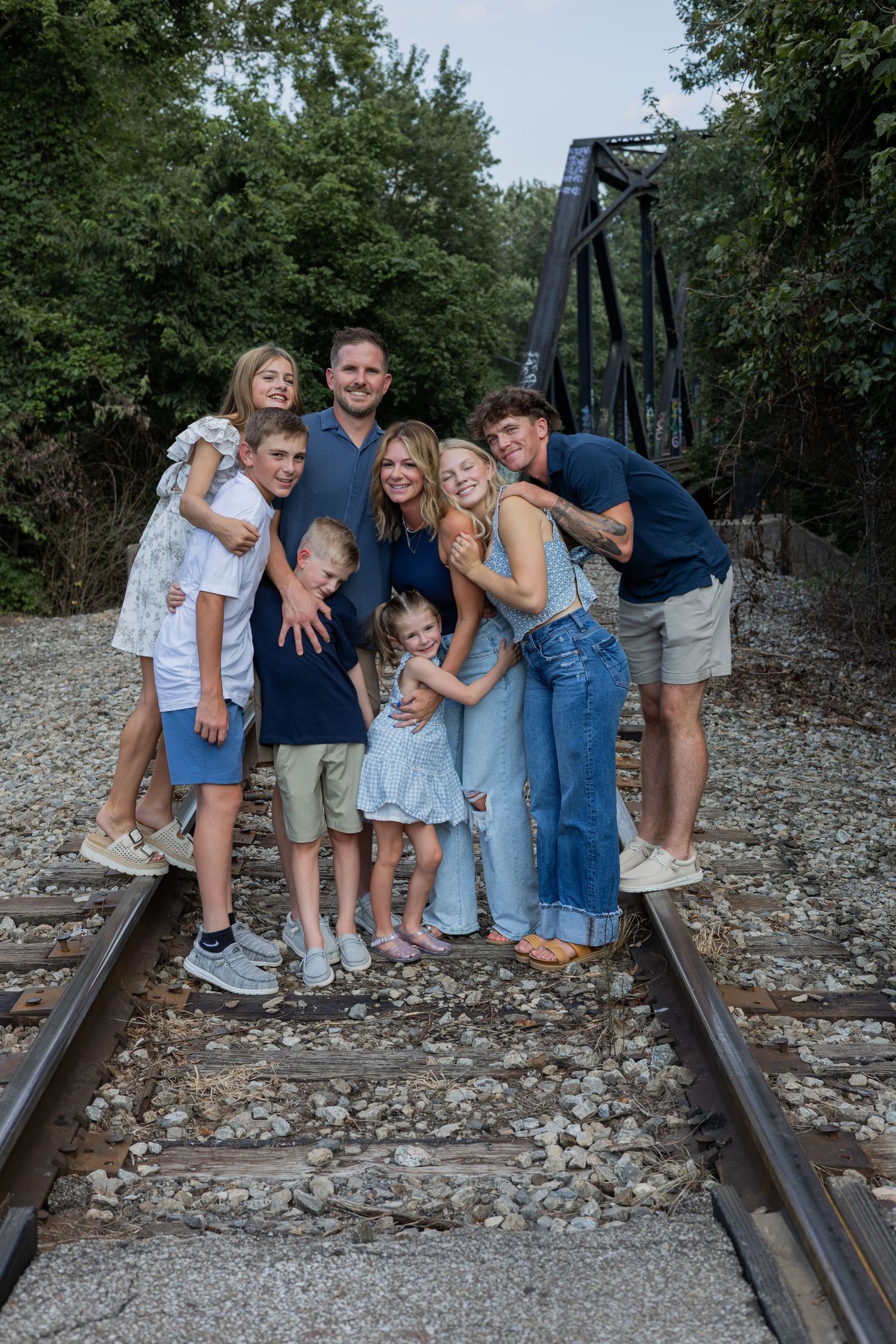 Candid family moments captured on rustic railroad tracks in natural setting.
