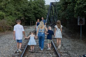 Family walking together on railroad tracks in coordinated casual outfits.