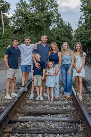 Extended family portrait on railroad tracks with coordinated blue and white clothing.