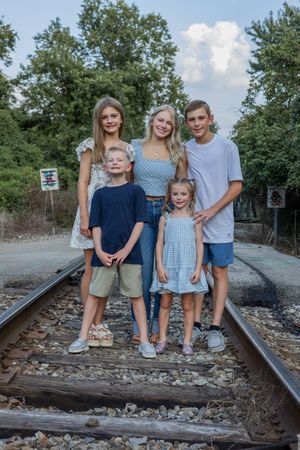 Family group poses casually on railroad tracks during outdoor photo session.