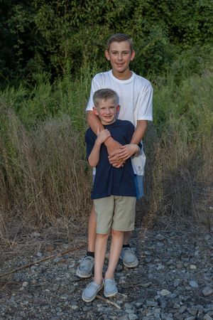 Casual portrait of children on rocky railroad tracks in natural setting.
