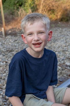 Young person in navy shirt shows playful expressions in outdoor portrait series.