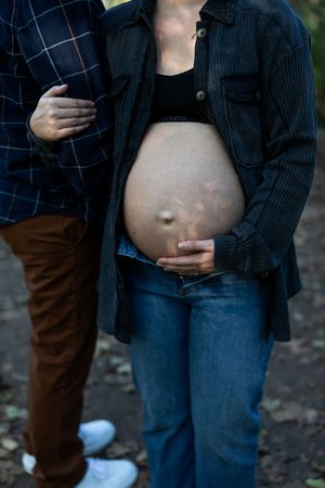 Close-up maternity photos showing a pregnant belly with hands gently resting on it.