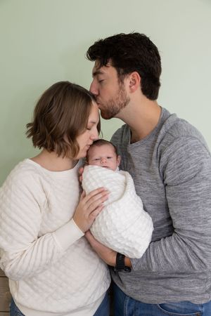 Tender moment between parents cradling their newborn baby in a cozy indoor setting.
