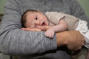 Close-up series of a sleeping newborn being held in gentle arms.