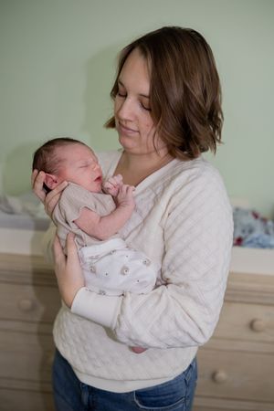 Mother in white sweater holding and bonding with newborn baby in various poses.