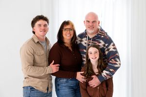 A group of people pose together for a series of casual family portraits against a light background.