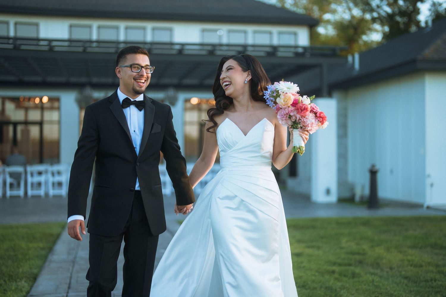 A happy couple walks together outdoors during their wedding celebration.