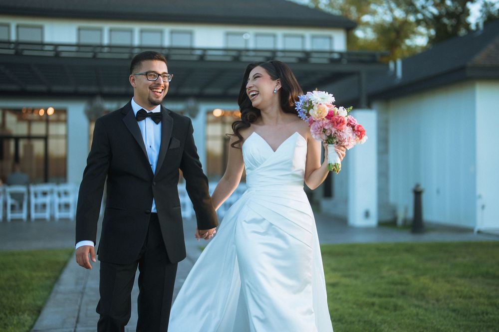 A happy couple walks together outdoors during their wedding celebration.