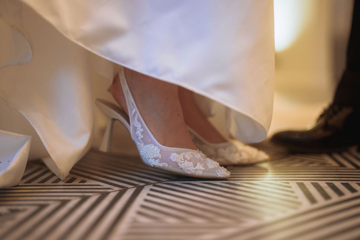 Detail shot of sparkly bridal shoes on a geometric patterned floor.