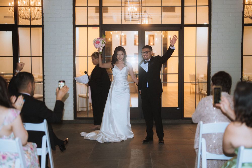 Wedding guests take photos as newlyweds celebrate at their reception entrance.