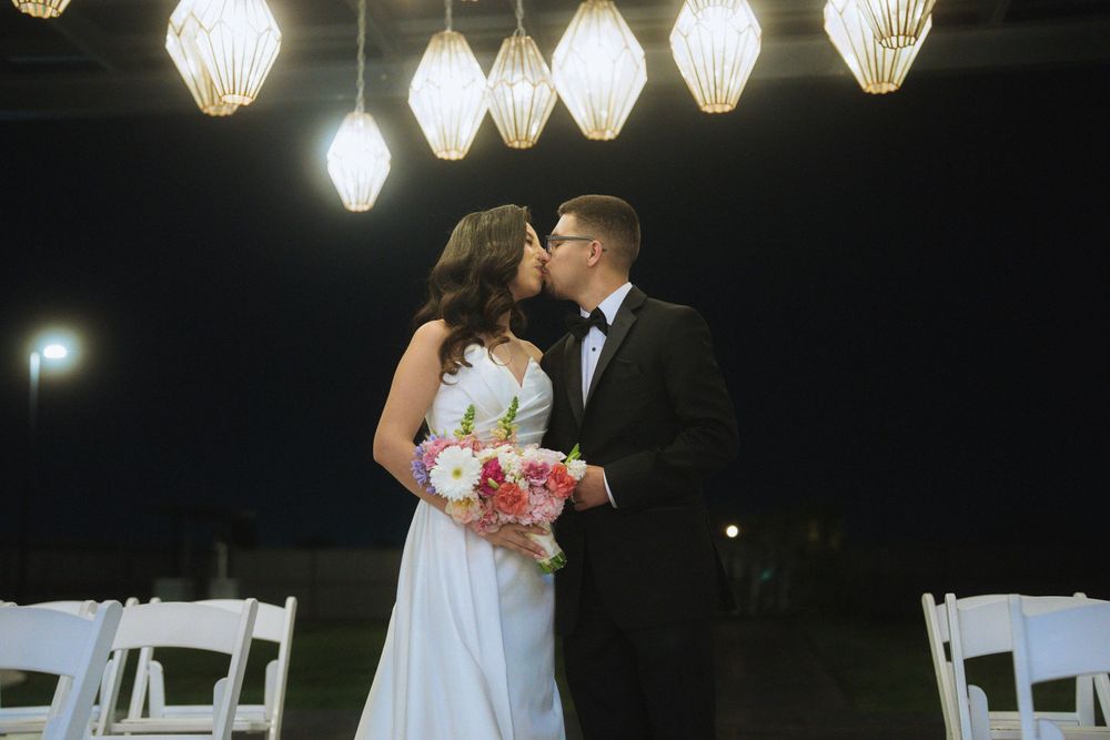 Romantic evening portrait of newlyweds under hanging diamond-shaped lanterns.